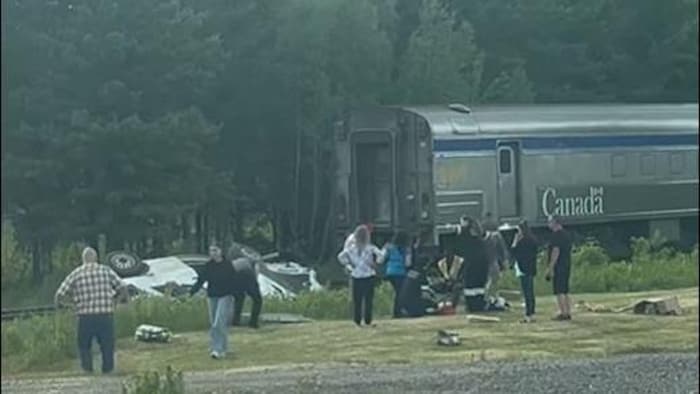 Des gens devant un train à l'arrêt et la carcasse d'une fourgonnette.