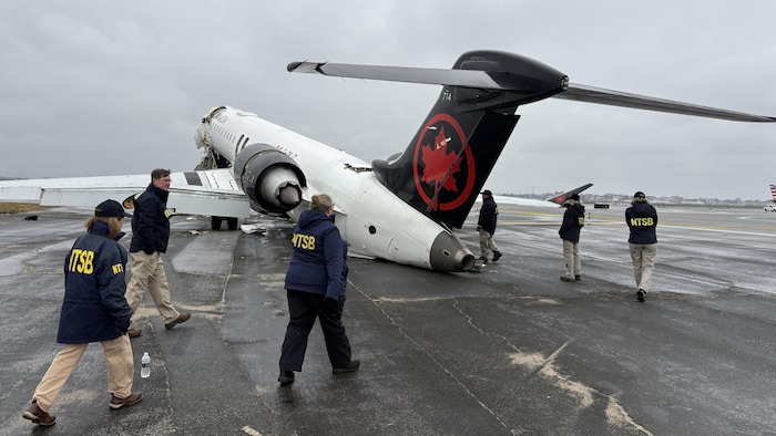 Une photo fournie par le NTSB montre des inspecteurs autour de l'avion écrasé à l'aéroport LaGuardia.