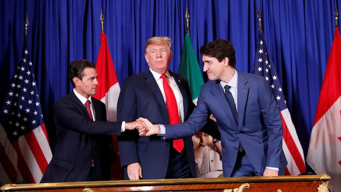 Le président américain Donald Trump, entouré d'Enrique Pena Nieto et de Justin Trudeau qui se serrent la main.
