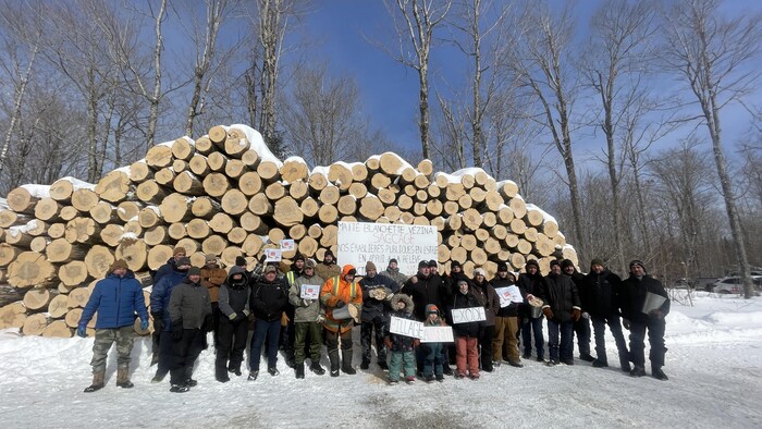 Des hommes prennent la pose devant des billots de bois d'érable. 