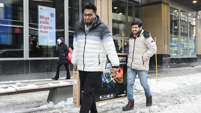 Deux hommes transportent un téléviseur. 