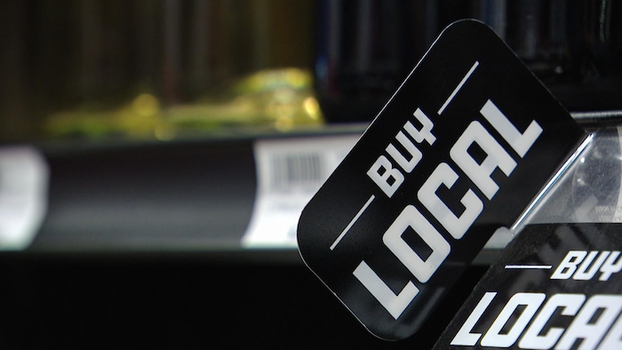 Une affiche indiquant « Buy Local » dans un magasin d'alcool de Regina, en Saskatchewan, le 13 août 2026.