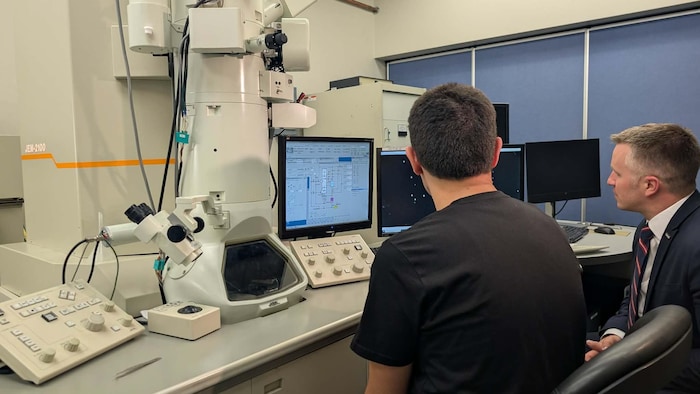 Des personnes utilisent un microscope électronique. 