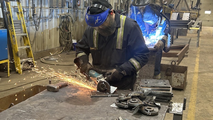 Des ouvriers travaillent sur une pièce d'acier.