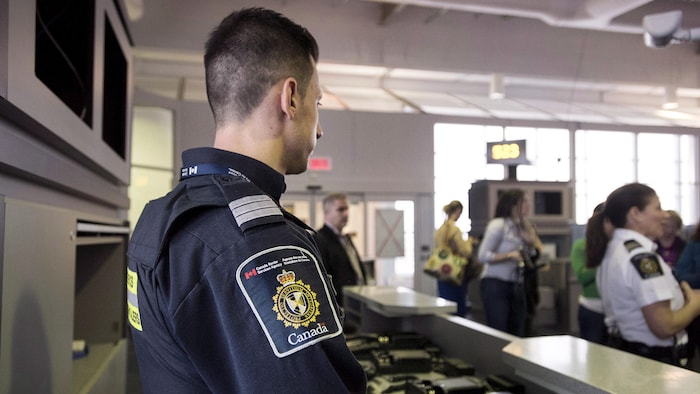 Un douanier canadien regarde des voyageurs.