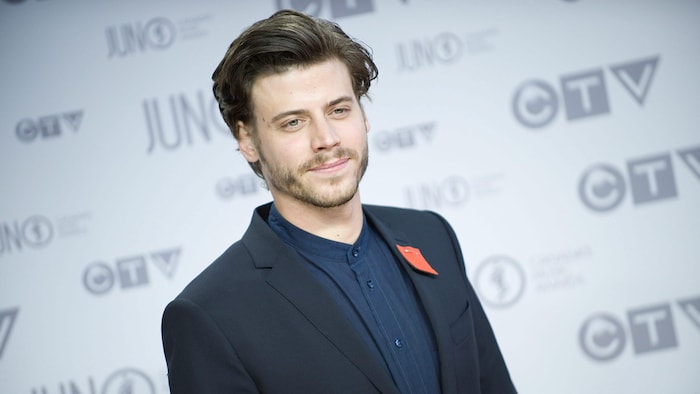 François Arnaud pose sur un tapis rouge.