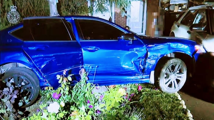 Un véhicule bleu est encastré dans une voiture blanche dans une allée.