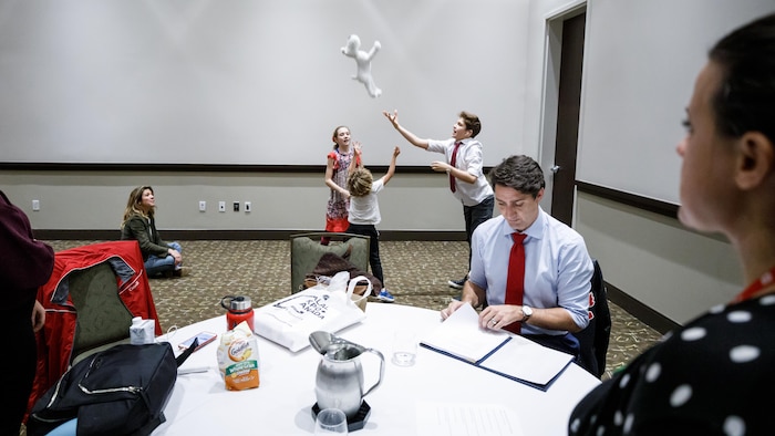Justin Trudeau travaille lors d'une intermission avant un rassemblement de campagne à Mississauga en 2019 pendant que ses enfants s'amusent à l'arrière-plan.