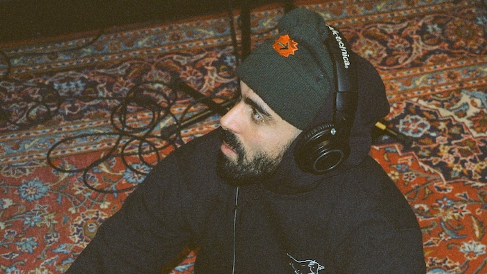 L'humoriste est assis avec un casque d'écoute sur la tête. 