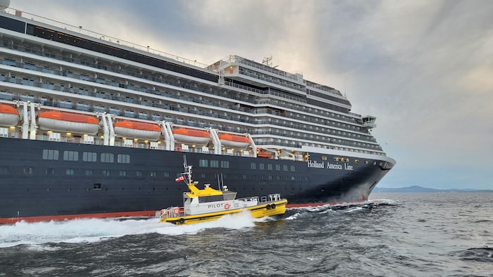 Un bateau-pilote à côté d'un bateau de croisière.
