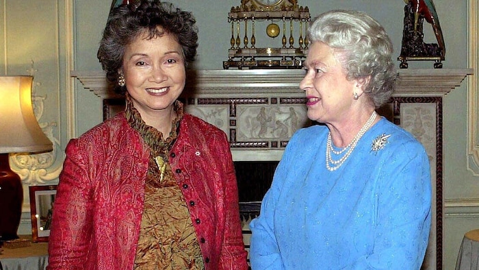 Adrienne Clarkson sourit, l'air détendu, au photographe sous le regard de la reine Élisabeth II.