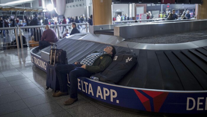 Un voyageur dort sur un carrousel à bagages à l'aéroport international Hartfield-Jackson d'Atlanta.