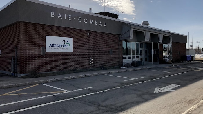 Le bâtiment de l'aéroport en brique brune sous un soleil radieux.