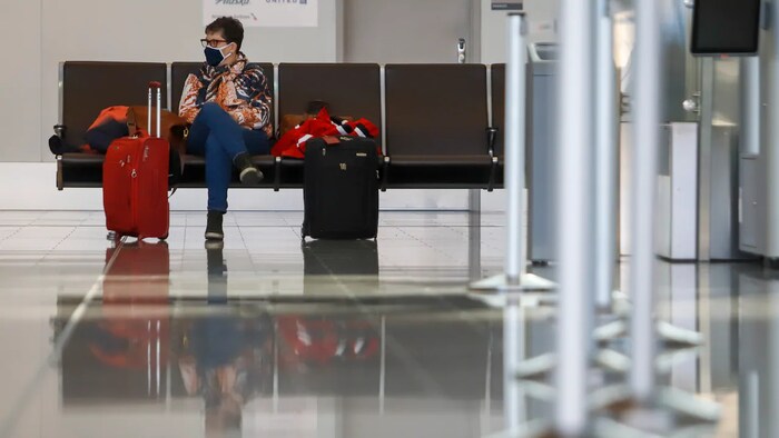 Une personne assise sur un banc dans un aéroport près de ses valises.