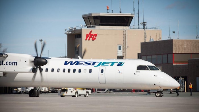 Un avion devant le bâtiment principal de l'aéroport.