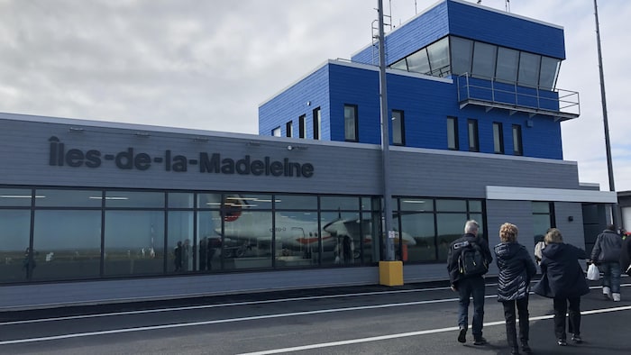 Des voyageurs marchent sur le tarmac de l'aéroport des Îles.