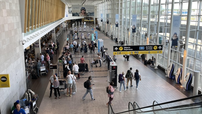 Des passagers dans l’aérogare principale de l’aéroport de Québec en été.