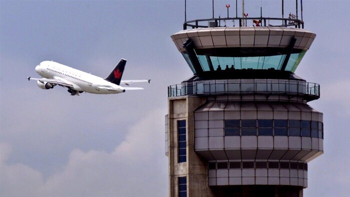 Un avion contourne la tour de contrôle de l'aéroport Pierre-Elliott-Trudeau (archives).