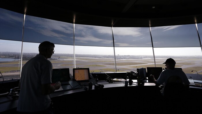 Des contrôleurs aériens sont visibles depuis leur tour de contrôle surplombant les pistes de l'aéroport international de Sydney en Australie.