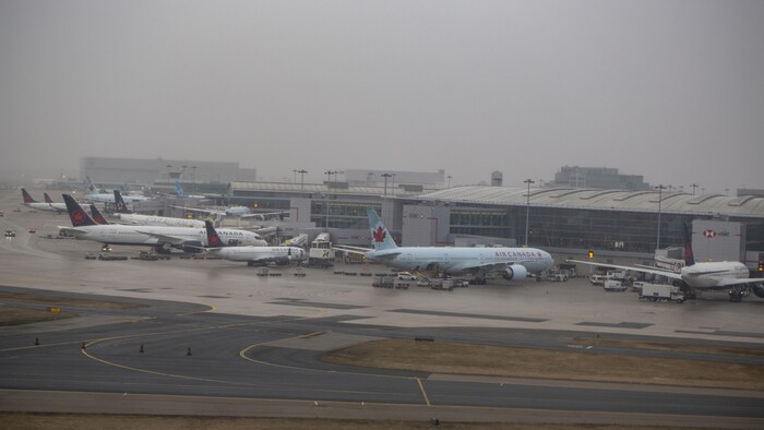Un avion d'Air Canada au sol par une journée brumeuse.