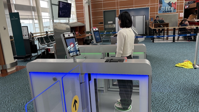Une femme est debout devant un scanner de comparaison faciale.