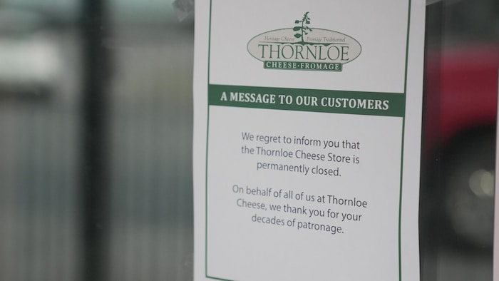 Une affiche dans une porte en verre indiquant que la fromagerie Thornloe est fermée de façon permanente.