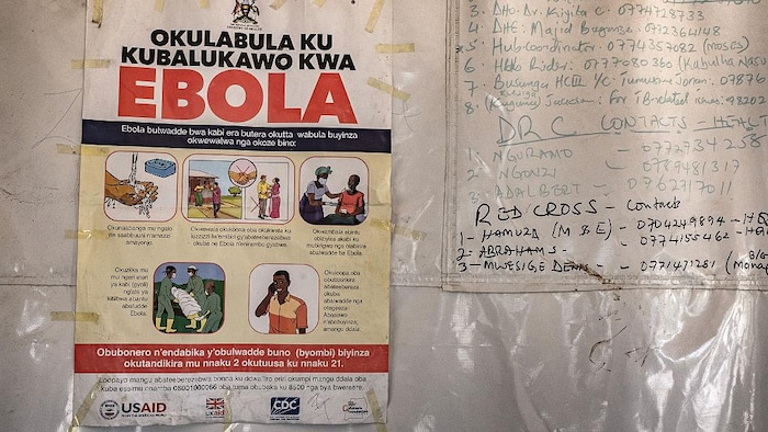 Une affiche indiquant les numéros d'urgence à composer pour des renseignements sur l'Ebola est accrochée à une tente au poste-frontière de Busunga, entre l'Ouganda et la République démocratique du Congo, à Bundibugyo, le 18 mai 2026. 