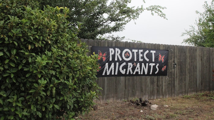 Une banderole disant «Protect Migrants» sur une clôture.