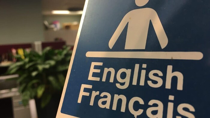 ملصق يحمل رسم موظف عند مكتب الاستقبال ويفيد بأنّ الخدمة مؤمنة بالفرنسية والإنكليزية.