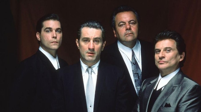 Quatre hommes portent des costumes et des cravates.