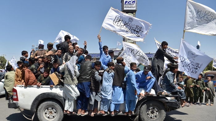 Des personnes célèbrent sur un camion, drapeaux à la main.
