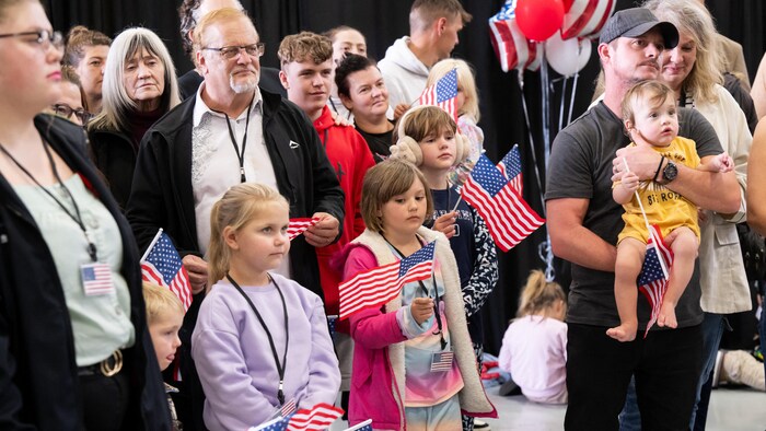 Des Blancs, dont des enfants, sont debout et plusieurs tiennent des drapeaux américains.