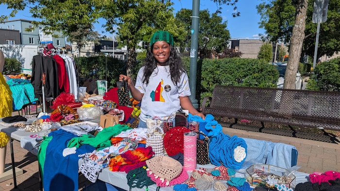 Stéphanie Mafo derrière son kiosque, montrant ses créations artisanales.