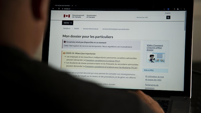 Une personne regarde le site de l'Agence du revenu du Canada sur un écran. La page l'informe qu'il ne peut temporairement consulter son dossier. 