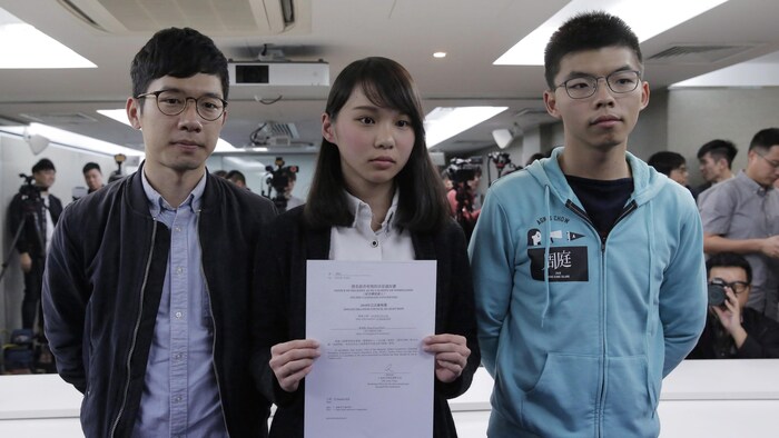 Agnes Chow, 21, a member of democracy Demosisto party, center, is accompanied by Joshua Wong, right, and Nathan Law, holds a notice from the Hong Kong government at a press conference in Hong Kong, Saturday, Jan. 27, 2018. The Hong Kong government says it has barred a young pro-democracy 1activist from an upcoming election because her party's political platform violates electoral laws, in the latest move by the semiautonomous Chinese city to squelch dissent. (AP Photo/Kin Cheung)