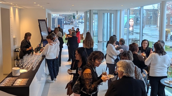 Des gens mangent et boivent dans le hall d'entrée de l'Agora des Arts.