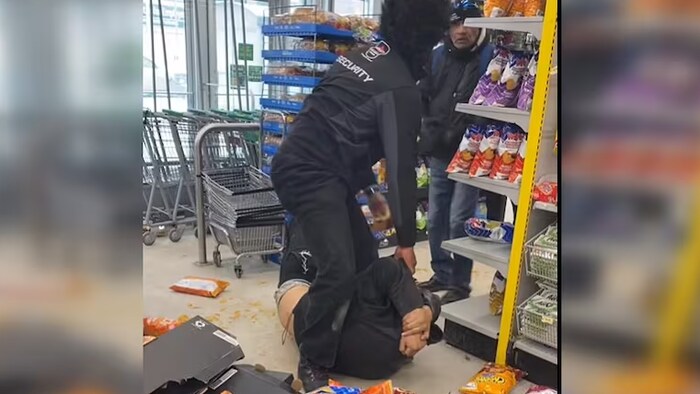 Un agent de sécurité frappe un homme à terre.