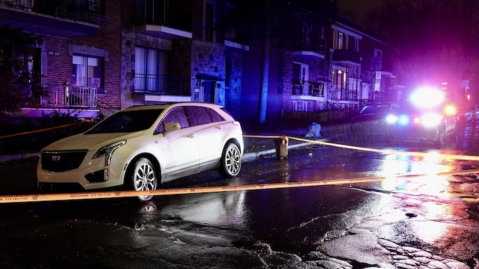 Une voiture de police éclaire une scène de crime dans la nuit.