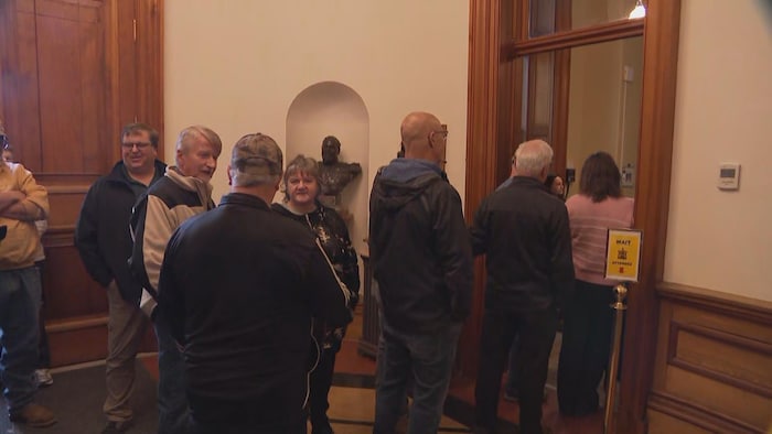 Des gens attendant d'entrer dans une salle, en file.