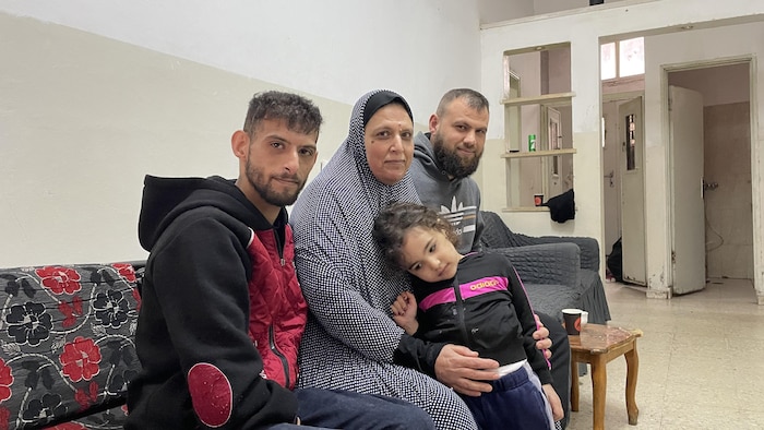 Ahmed Dar-Khalil assis sur un sofa avec sa mère, qui tient sa nièce contre elle, et son frère.