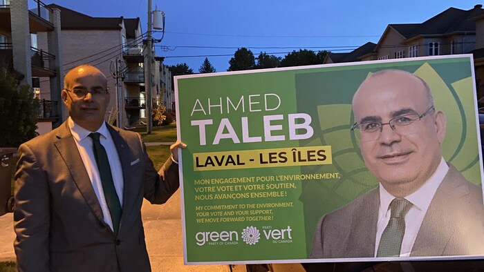 Un homme tient une pancarte électorale.