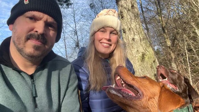 Portrait d'une femme blonde souriante aux cheveux longs et de son mari avec leur chien marron