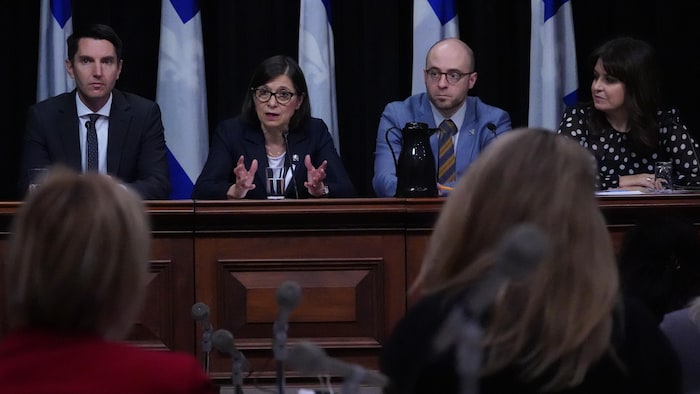 Quatre personnes derrière un bureau durant une conférence de presse.