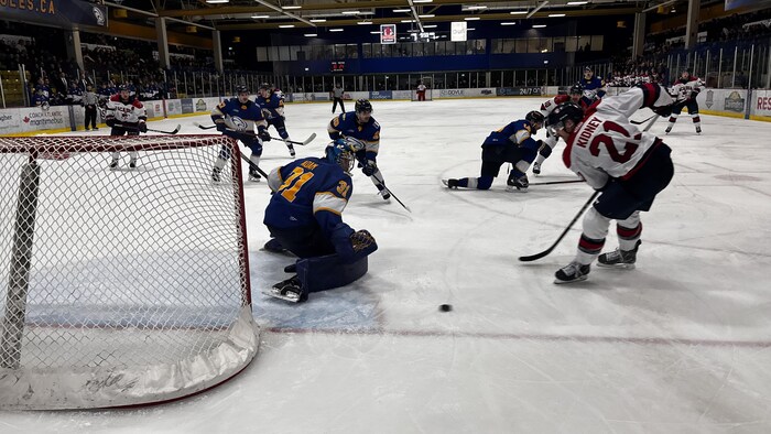 Des joueurs de hockey s'affrontent sur la glace dans un aréna. 