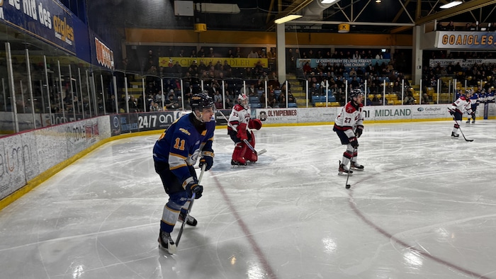 Des joueurs de hockey s'affrontent sur la glace dans un aréna. 