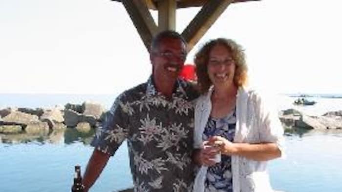 Pat Dunn et son époux sourient sur un quai devant l'océan.