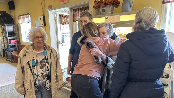 Paule Desgagné serre dans ses bras une aînée. Autour d'elle, des personnes âgées sourient.