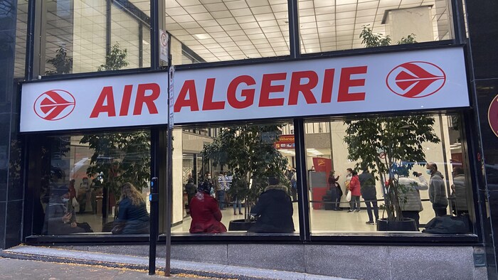 Des personnes assises et d'autres debout dans le hall d'un immeuble de bureaux.