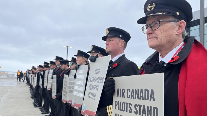 Des pilotes en uniforme forment une ligne à l'extérieur de l'aéroport international de Calgary.