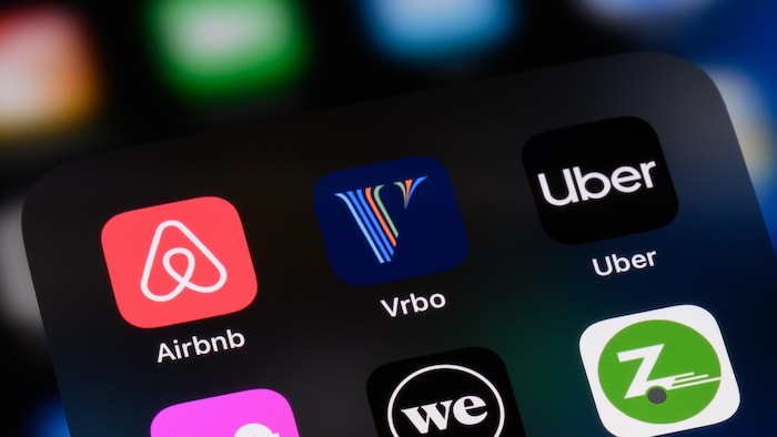 Les icônes des applications d'Airbnb, Vrbo, Uber, Lyft, WeWork et Zipcar apparaissent sur l'écran d'un téléphone cellulaire.
